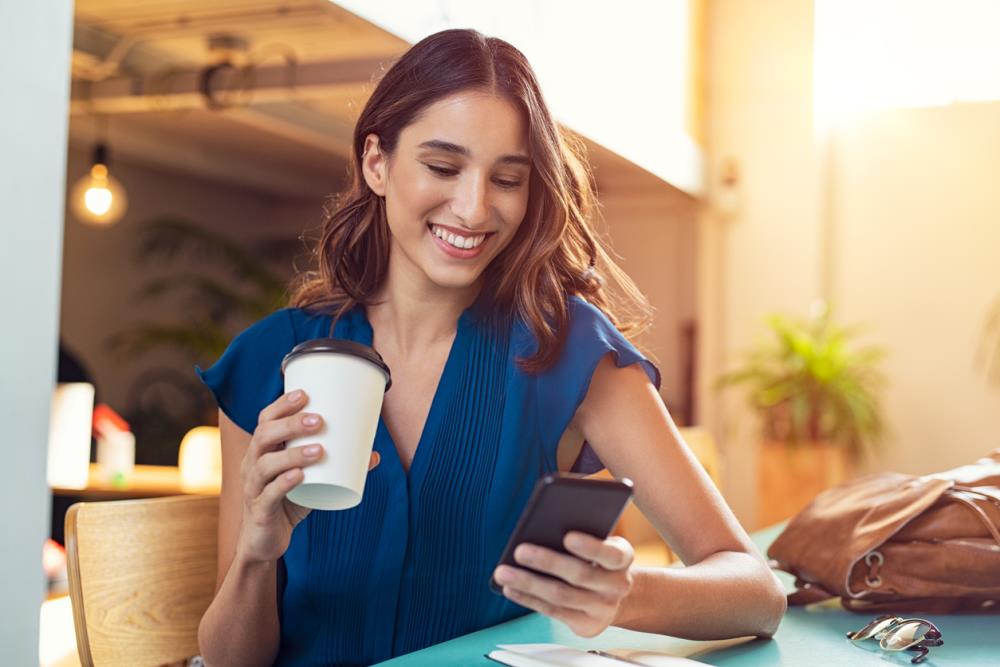 woman with coffee looking at phone