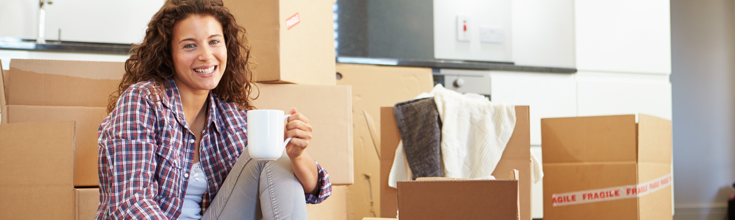 girl holding coffee sitting on floor with moving boxes